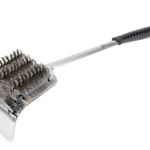 A grill brush with a handle on top of it.