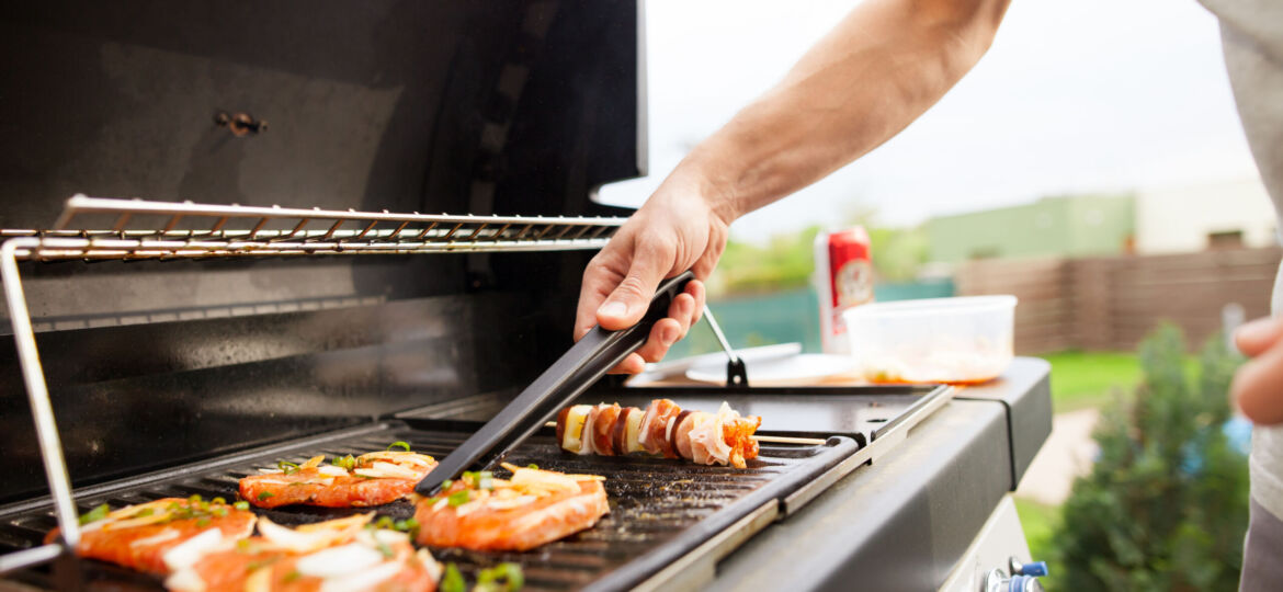 A person grilling food on top of an outdoor grill.