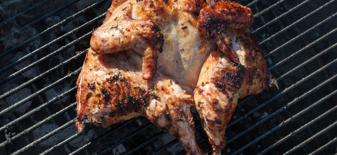 A chicken is cooking on the grill.