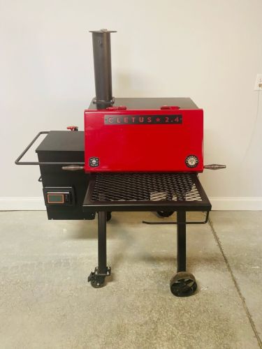 A red grill sitting on top of a metal cart.