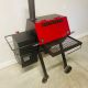A red and black grill sitting on top of the floor.