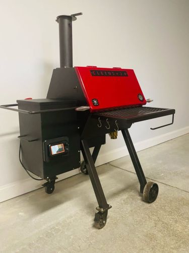 A red grill sitting on top of a metal cart.