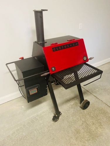 A red and black grill sitting on top of concrete.